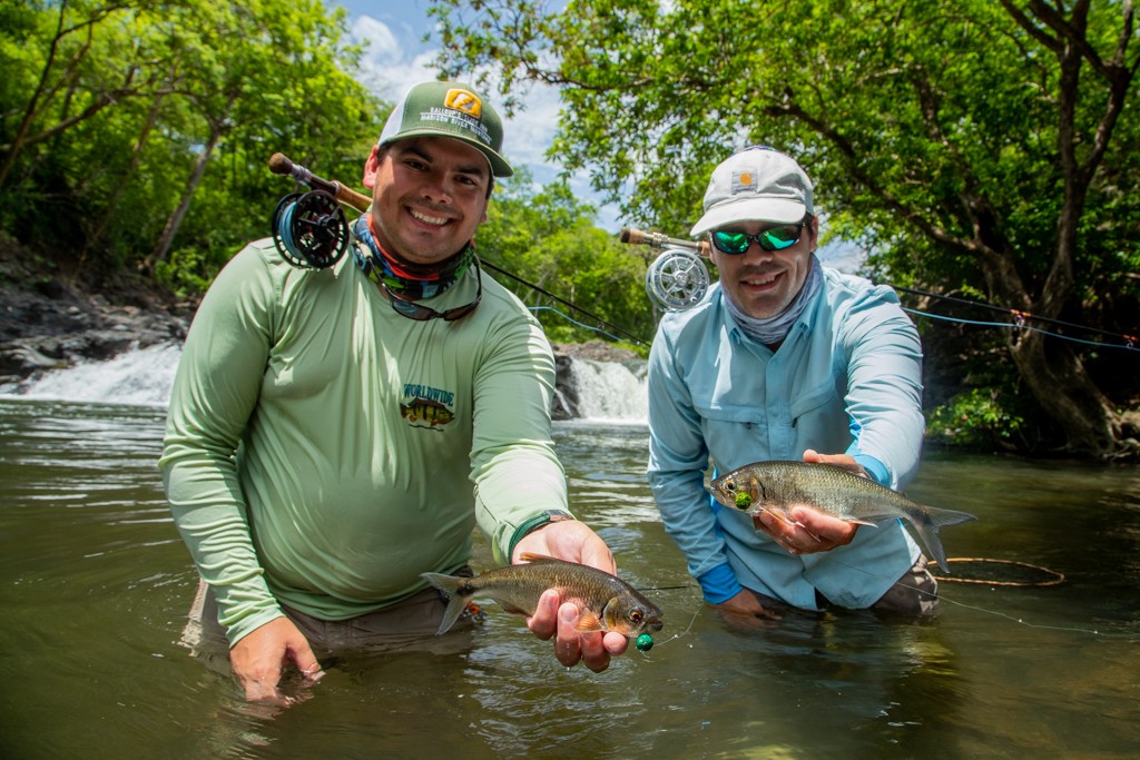Two Anglers holding machaca fishing in front of waterfall
